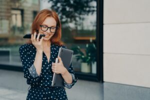 Female entrepreneur walks outdoor records voice message in social media via smartphone